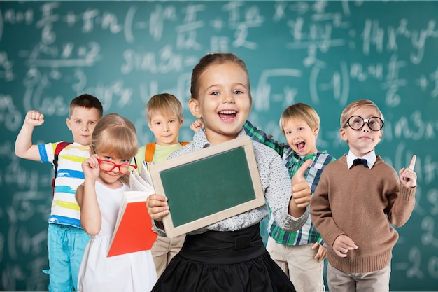 Enfants heureux posant avec fond de tableau noir