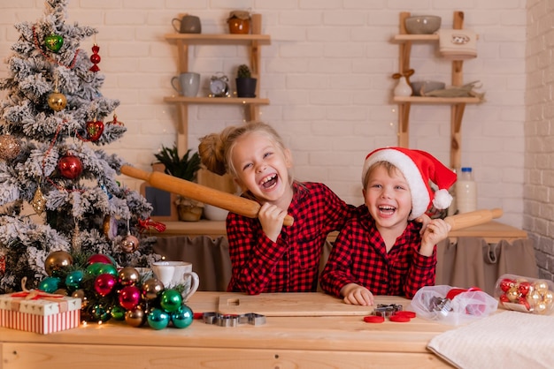 Des enfants heureux préparent des biscuits de Noël à la maison dans la cuisine