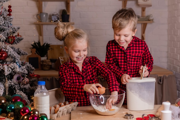 Des enfants heureux préparent des biscuits de Noël à la maison dans la cuisine