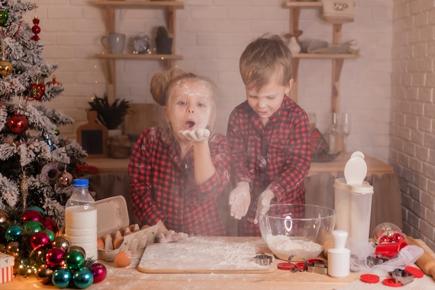 Des enfants heureux préparent des biscuits de Noël à la maison dans la cuisine