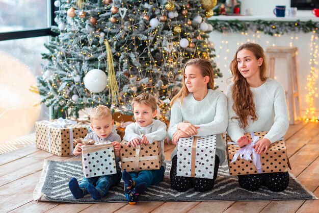 Enfants heureux près de l'arbre de Noël avec les boîtes présentes