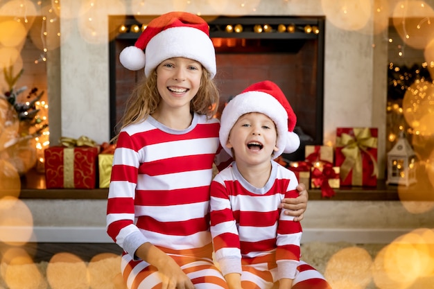 Enfants heureux près de la cheminée à Noël. Les enfants s'amusent à la maison.