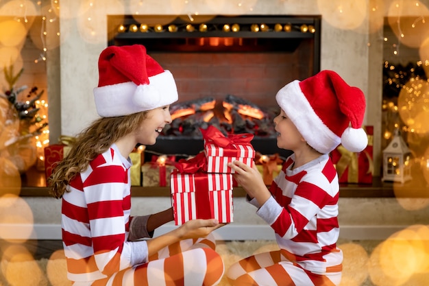 Enfants heureux près de la cheminée à Noël. Les enfants s'amusent à la maison.