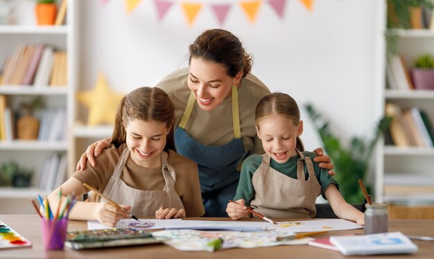 Des enfants heureux et un professeur à la classe d'art Une femme et des enfants peignent ensemble