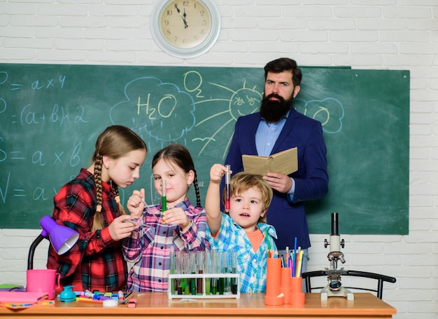 Photo enfants heureux professeur de retour à l'école enfants en blouse de laboratoire apprenant la chimie dans le laboratoire de l'école faisant des expériences avec des liquides dans le labo de chimie laboratoire de chimie pharmacien confiant