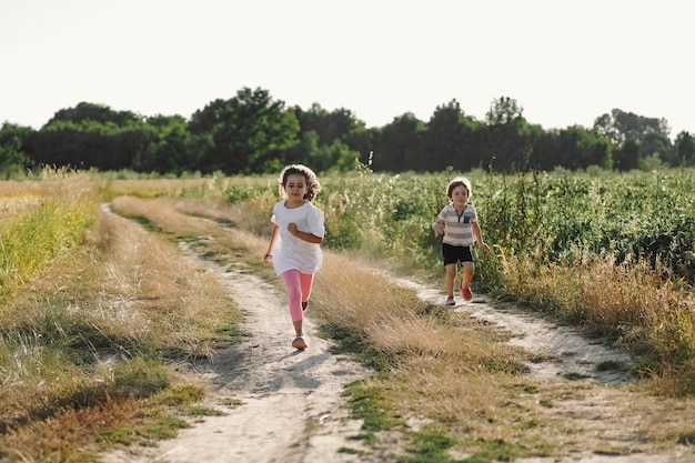 Enfants heureux qui courent sur le pré en été dans la nature.