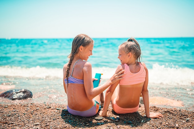 Des enfants heureux s’appliquent les uns aux autres sur la plage. Le concept de protection contre les rayons ultraviolets