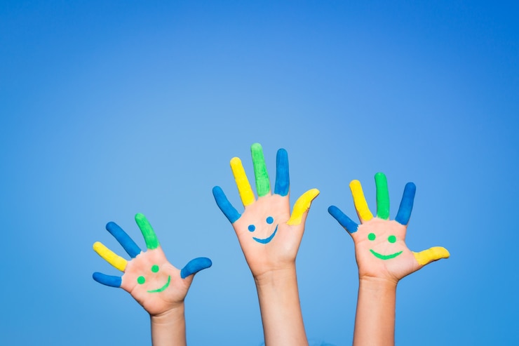 Photo enfants heureux avec smiley sur les mains sur fond de ciel bleu d'été