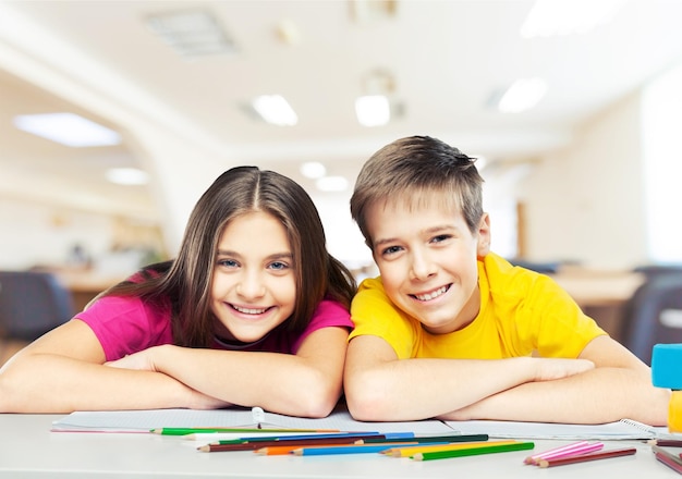 Enfants heureux souriants assis près de la table pendant la leçon