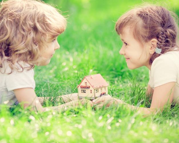 Enfants heureux tenant une maison modèle dans les mains