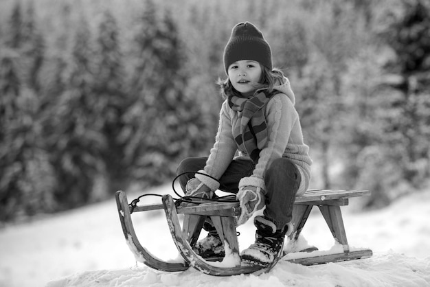 Enfants d'hiver enfant garçon glissant sur un traîneau dans un parc enneigé petit garçon jouant à l'extérieur dans la neige