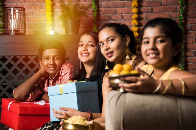 Enfants indiens célébrant Diwali, Deepawali, Bhai Dooj ou Rakhi ou Raksha Bandhan avec rangoli de fleurs, cadeaux, diya