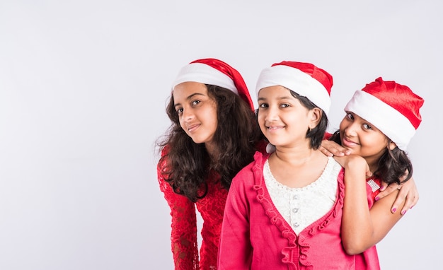 Enfants indiens célébrant Noël avec des cadeaux, un arbre et un chapeau de père Noël rouge, isolé sur fond blanc