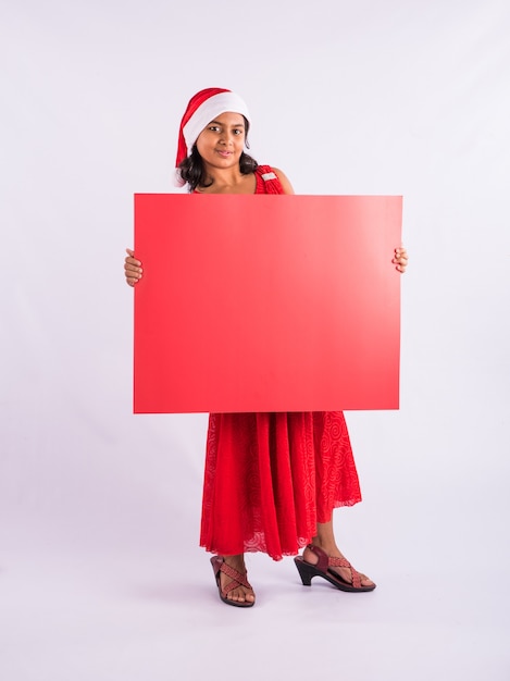 Enfants indiens célébrant Noël avec des cadeaux, un arbre et un chapeau de père Noël rouge, isolé sur fond blanc