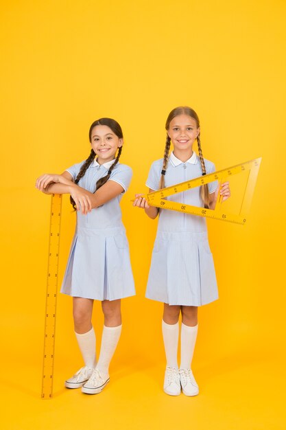 Enfants intelligents à la leçon de tige. les filles aiment la géométrie. vieille école. éducation moderne. amis heureux en uniforme rétro. mode enfant vintage. retour à l'école. les petites filles détiennent des outils mathématiques. Disciplines STIM.