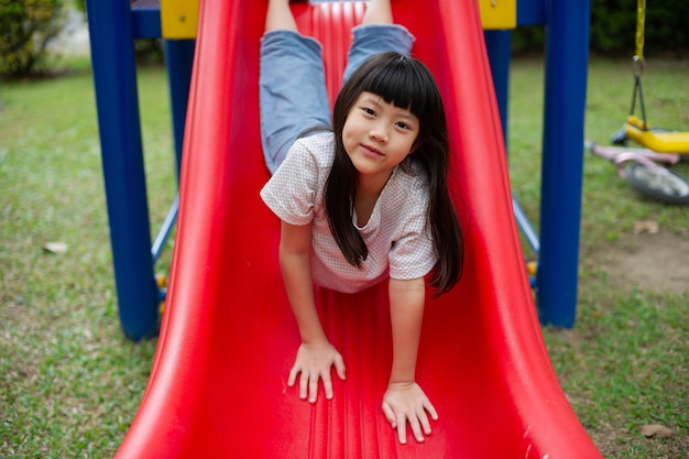 Enfants jouant sur l'aire de jeux fille heureuse jouant des diapositives