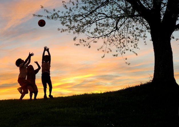 Enfants jouant au coucher du soleil, silhouettes, liberté et bonheur