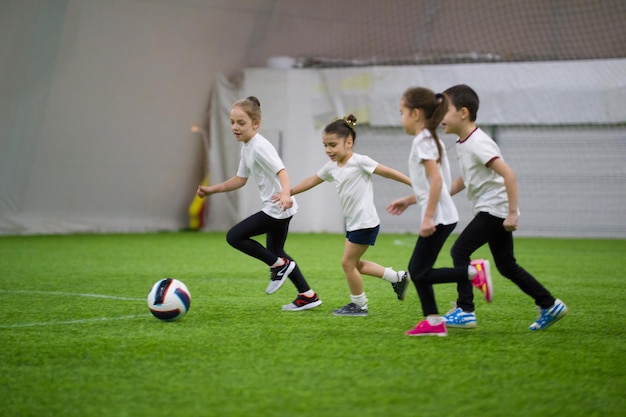 Enfants jouant au football à l'intérieur des enfants courant sur le terrain après le ballon