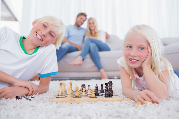 Enfants jouant aux échecs devant leurs parents