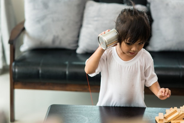 Enfants jouant avec une boîte de conserve et un téléphone à cordes comme concept de communication