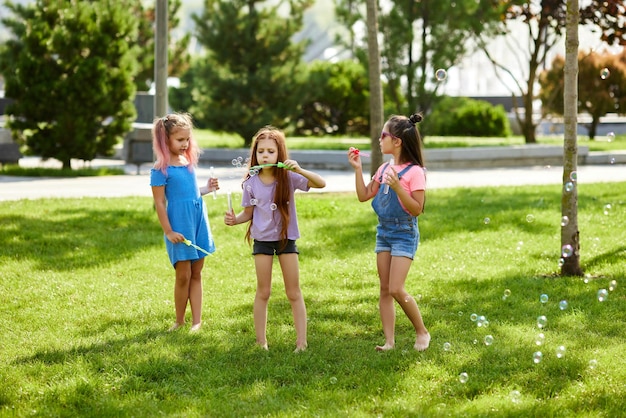 Enfants jouant avec des bulles de savon dans le parc en journée d'été ensoleillée