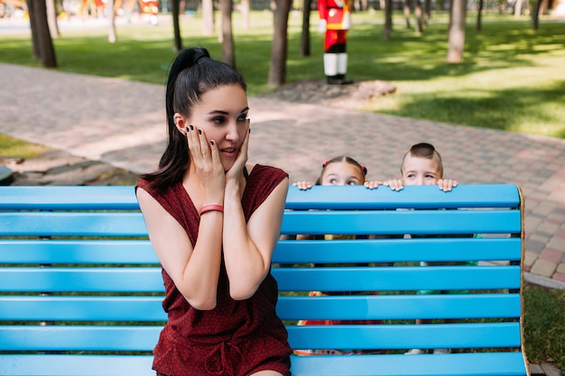 Enfants jouant à cache-cache avec leur mère dans le parc. Loisirs en famille.