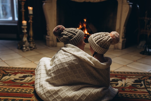 Enfants jouant ensemble près de la cheminée, souriant et s'amusant en hiver. Noël, nouvel an, concept d'hiver