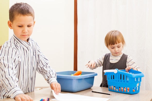 Enfants jouant avec des fruits et légumes en plastique à la maternelle