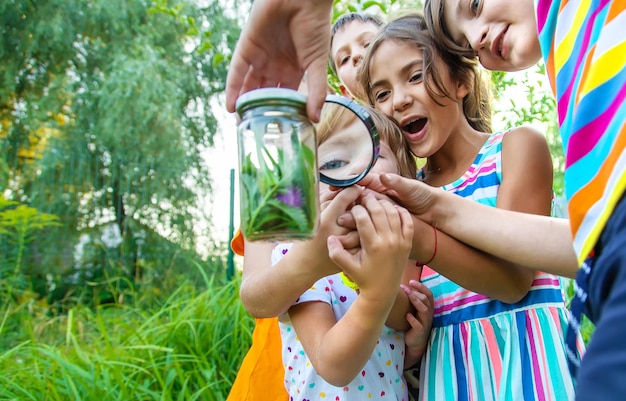 Photo des enfants jouant avec une loupe dans le jardin.