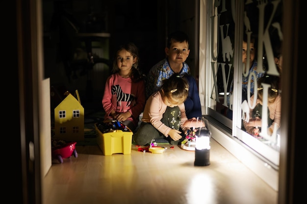 Enfants jouant à la maison pendant une panne d'électricité à l'aide d'une lanterne