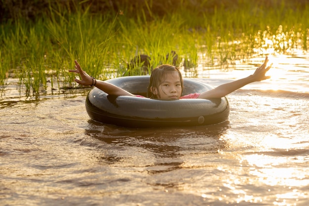 Enfants jouant et nageant dans le canal d'une ferme biologique à la campagne