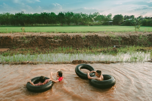 Enfants jouant et nageant dans le canal d'une ferme biologique à la campagne