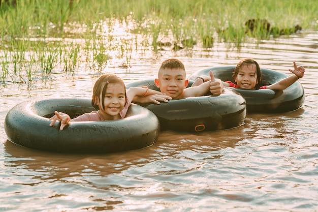 Enfants jouant et nageant dans le canal d'une ferme biologique à la campagne