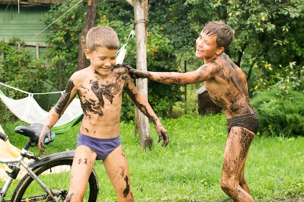 Les enfants jouent dans une flaque d'eau, se salissent dans la boue. Tout se passe pendant les vacances d'été à l'arrière