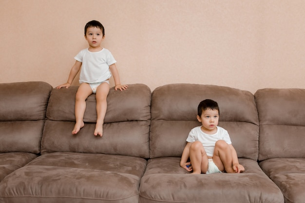 Les enfants jouent dans la pièce à la maison. des jumeaux de deux ans sautent sur le canapé