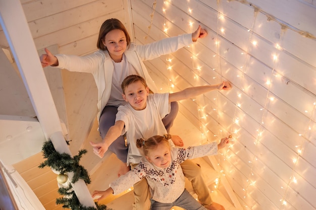 Les enfants jouent sur l'escalier décoré de Noël dans la maison décorée du Nouvel An, la famille, les vacances d'hiver et le concept de personnes