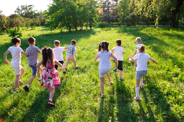 Les enfants jouent à l'extérieur en courant et en s'amusant sur un terrain en herbe