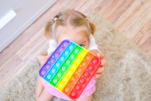 Les enfants jouent avec le jouet sensoriel pop it. Soulagement du stress et de l'anxiété. Jeu de remuement en silicone tendance pour les enfants stressés
