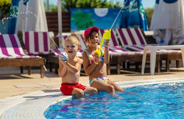 Les enfants jouent avec des pistolets à eau dans la piscine. Mise au point sélective. L'eau.