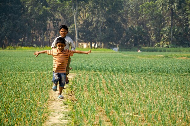 Des enfants jouent sur la terre Un magnifique paysage du Bangladesh Deux enfants dansent joyeusement sur le chemin Village Puijor City Rajbari Bangladesh Capture 522023
