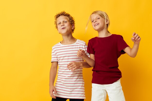 Enfants joyeux debout côte à côte posant des émotions d'enfance sur fond jaune