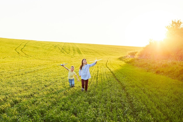 Des enfants joyeux et heureux jouent sur le terrain et s'imaginent être des pilotes par une journée d'été ensoleillée Les enfants rêvent de voler et d'aviation