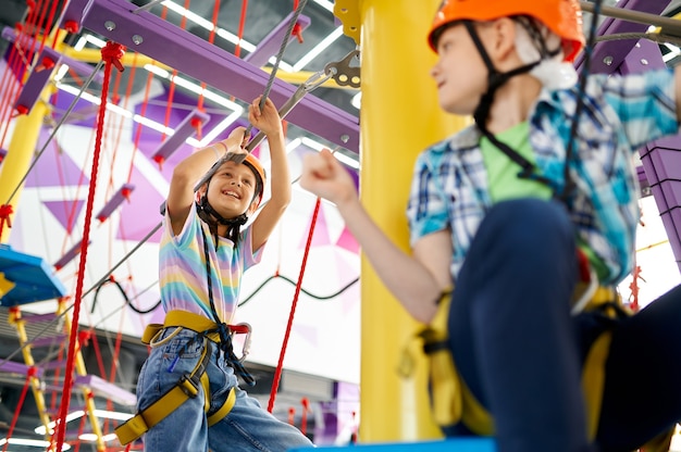 Enfants joyeux sur la tyrolienne dans le centre de divertissement. Garçon et fille s'amusant dans la zone d'escalade, les enfants passent le week-end sur l'aire de jeux, enfance active