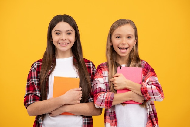 Des enfants joyeux vont faire leurs devoirs avec des livres. étudiant adolescent souriant. éducation. lycée. amis filles avec ordinateur portable. retour à l'école. adolescents prêts à étudier. enfance heureuse.