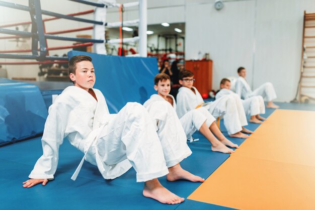 Les enfants de judo, les enfants en kimono pratiquent l'art martial dans le hall. Petits garçons et filles en uniforme sur l'entraînement sportif