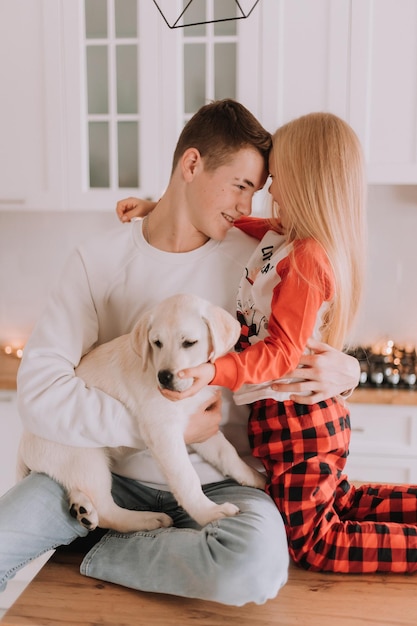 Les enfants avec leur chien bien-aimé sont assis dans la cuisine de Noël. passe-temps familial. mode de vie. frère et soeur, garçon et fille jouent et s'amusent avec un animal de compagnie. espace pour le texte. Photo de haute qualité