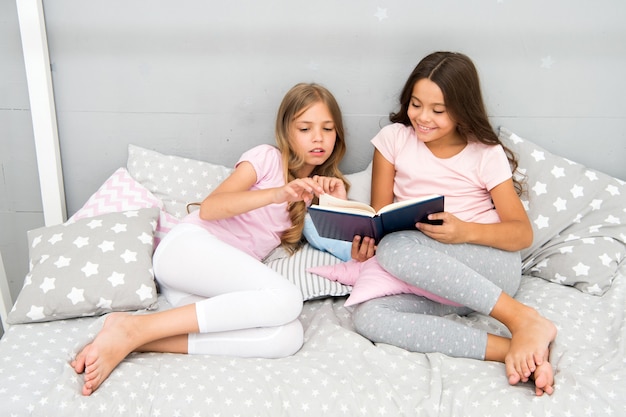 Les Enfants Lisent Un Livre Au Lit. Tradition Familiale. Les Meilleures Amies Des Filles Lisent Un Conte De Fées Avant De Dormir. Les Meilleurs Livres Pour Enfants. Lire Avant De Se Coucher Peut Aider à Mieux Dormir La Nuit. Des Histoires Que Chaque Enfant Devrait Lire.