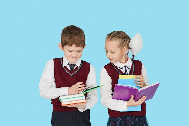 Enfants avec des livres sur un mur bleu.