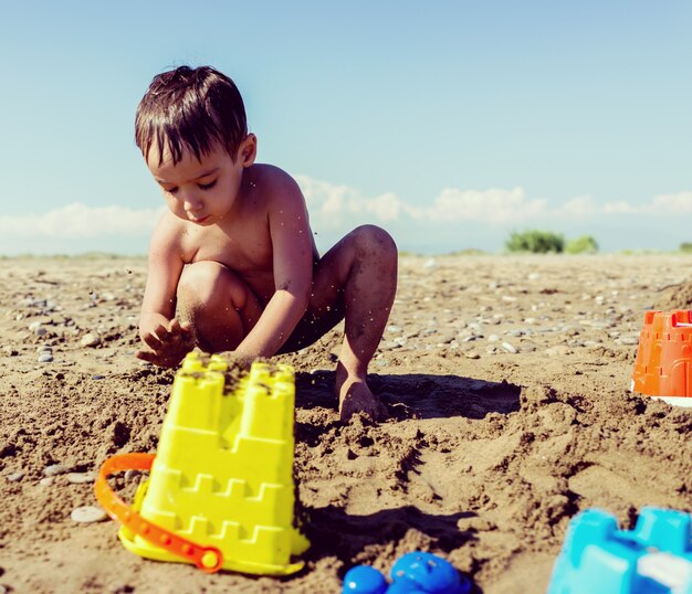 Enfants ludiques sur les vacances de sable de plage d&#39;été s&#39;amuser et temps heureux