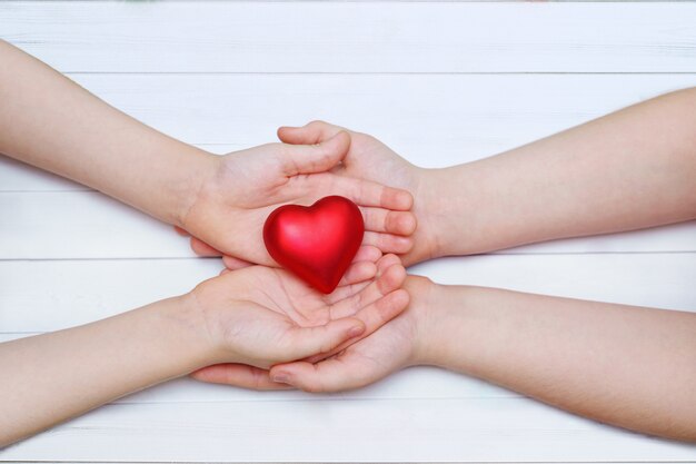 Enfants à la main avec un coeur rouge.